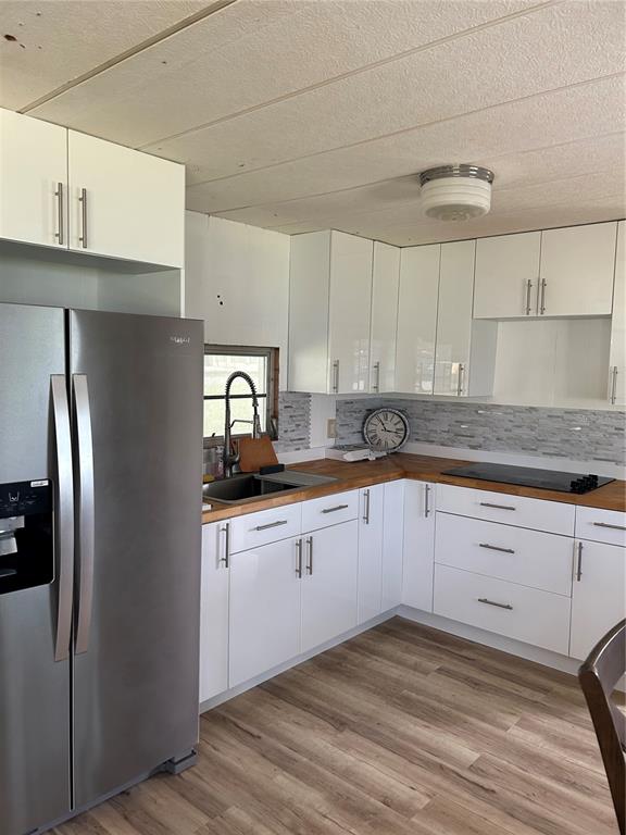 A kitchen features white cabinets, a stainless steel refrigerator, and wood-look flooring — 14750 OLD US HIGHWAY 441, TAVARES, FL