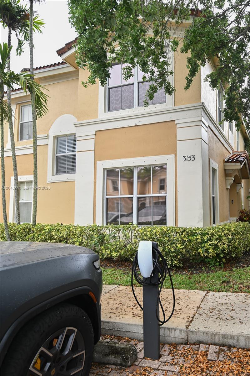 A two-story tan stucco building features a white-trimmed exterior and an electric vehicle charging station — 3153 SW 129th Ter, Miramar FL 33027, MIRAMAR, FL
