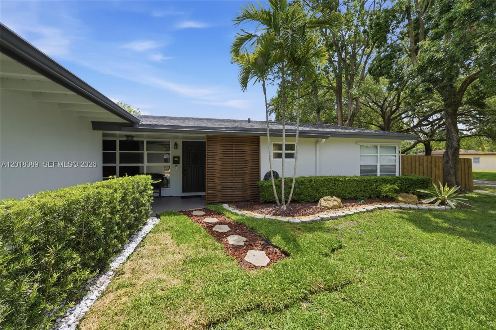 The exterior of a single-story home features a palm tree, a stone path, and landscaping — 109 S 57th Ave, Hollywood FL 33023, HOLLYWOOD, FL