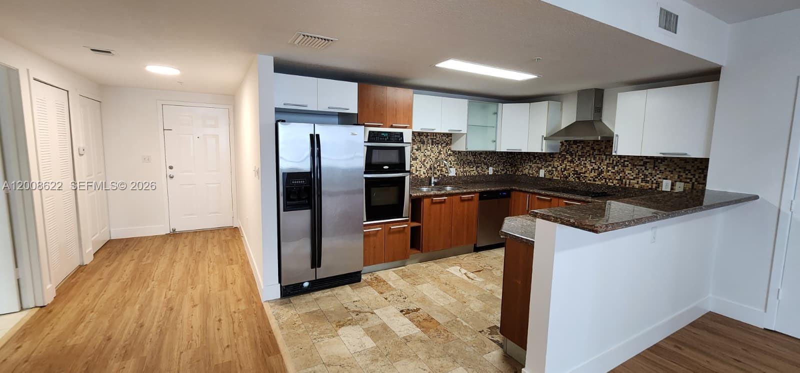 This kitchen features a mix of white and wood cabinets, stainless steel appliances, and tile flooring — 170 SE 14th St # 1408, Miami FL 33131, MIAMI, FL