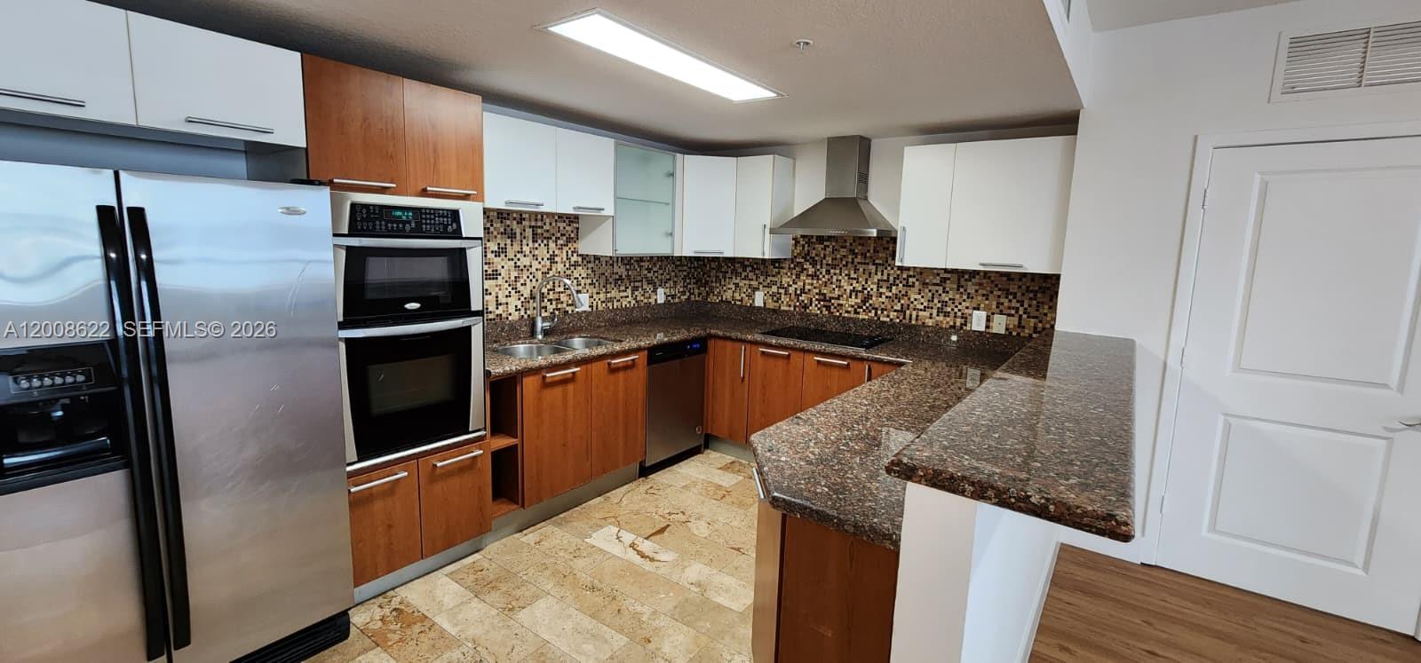 A kitchen features wood and white cabinetry, granite countertops, stainless steel appliances, and tile flooring — 170 SE 14th St # 1408, Miami FL 33131, MIAMI, FL
