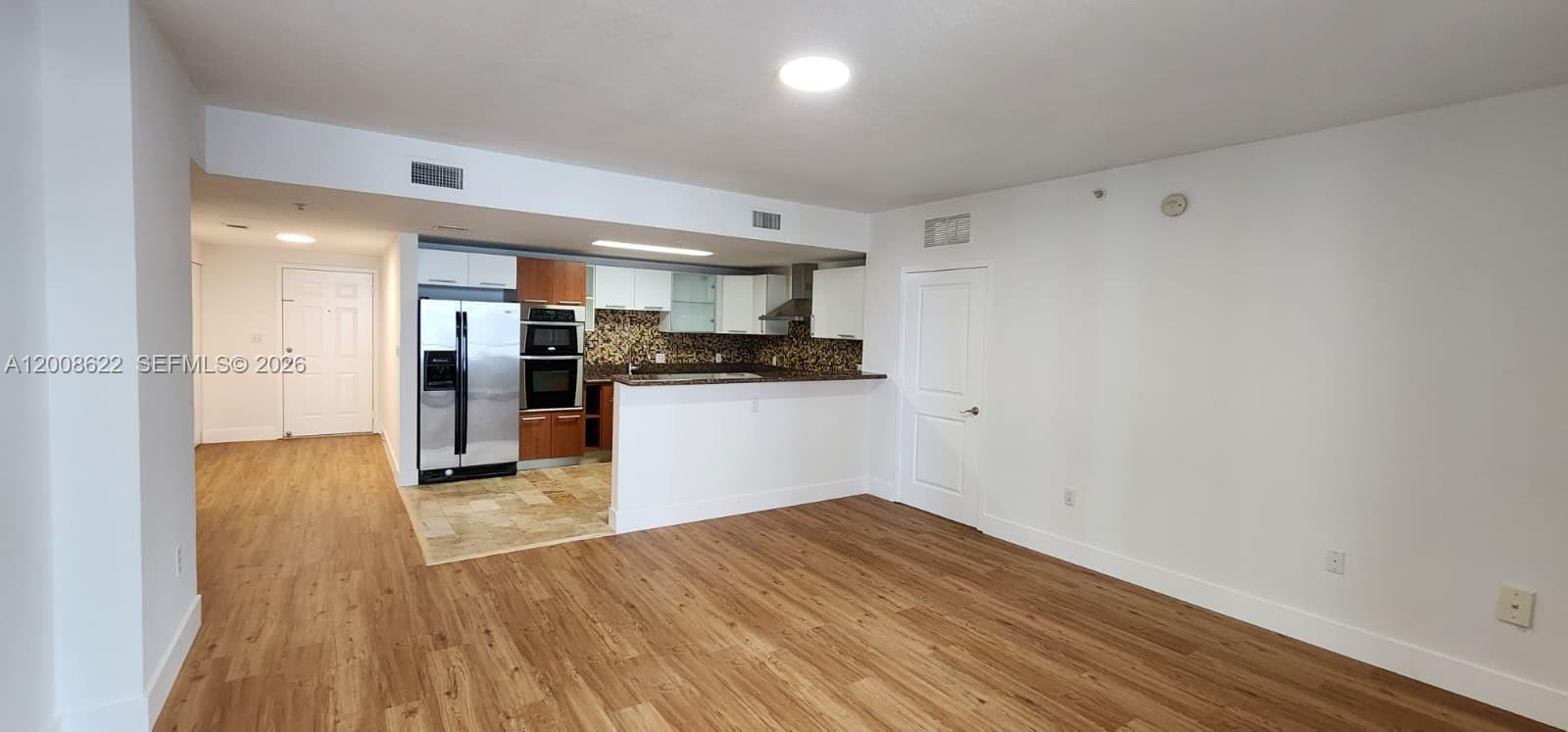 This living area features wood-look flooring and an open kitchen with stainless steel appliances — 170 SE 14th St # 1408, Miami FL 33131, MIAMI, FL