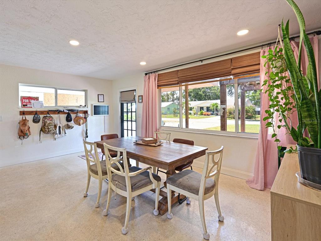 A dining room features a wooden table, four chairs, and a large window with curtains — 5812 2ND AVE DR NW, BRADENTON, FL