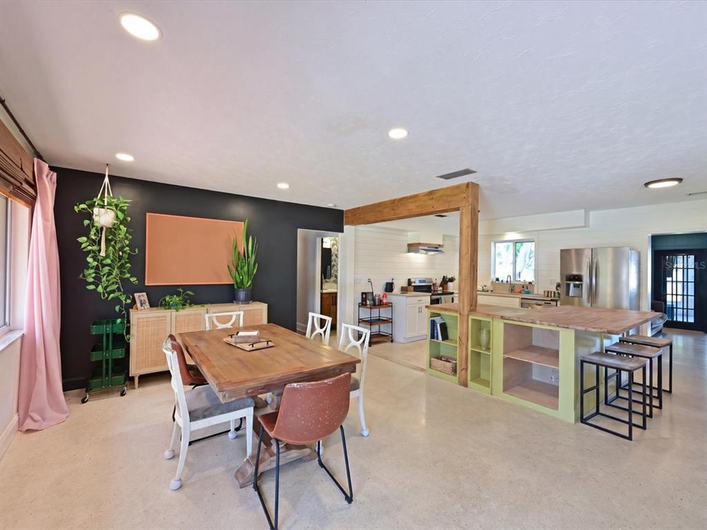 A dining area with a wooden table and black accent wall opens into a kitchen — 5812 2ND AVE DR NW, BRADENTON, FL