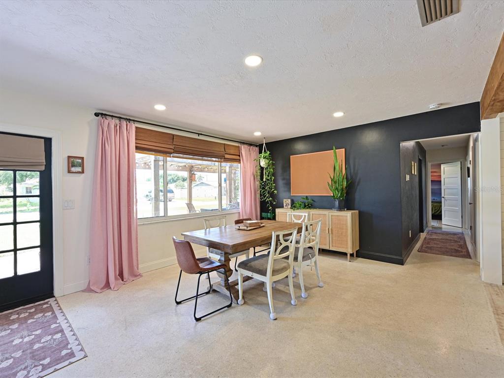 A dining room features a wooden table, mixed seating, pink curtains, and a black accent wall — 5812 2ND AVE DR NW, BRADENTON, FL