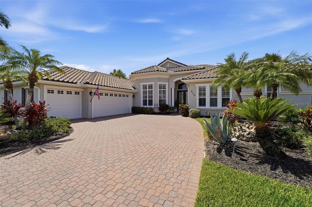 A single-story house with a paved driveway, a three-car garage, and palm trees — 515 SAND CRANE COURT, BRADENTON, FL