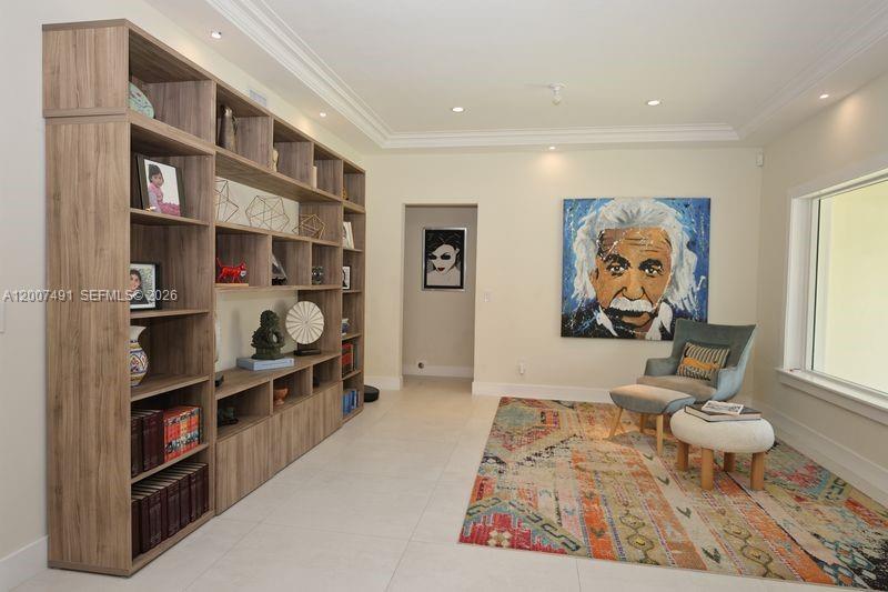 A room with light tile floors, a large wooden bookshelf, and a colorful area rug — 5620 Alton Rd, Miami Beach FL 33140, MIAMI BEACH, FL