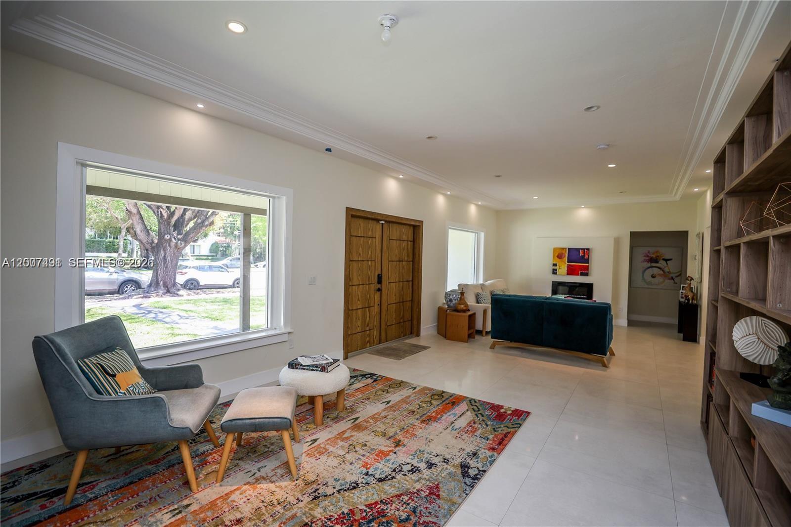 A living room features a large window, double wood doors, tile floors, and built-in shelving — 5620 Alton Rd, Miami Beach FL 33140, MIAMI BEACH, FL