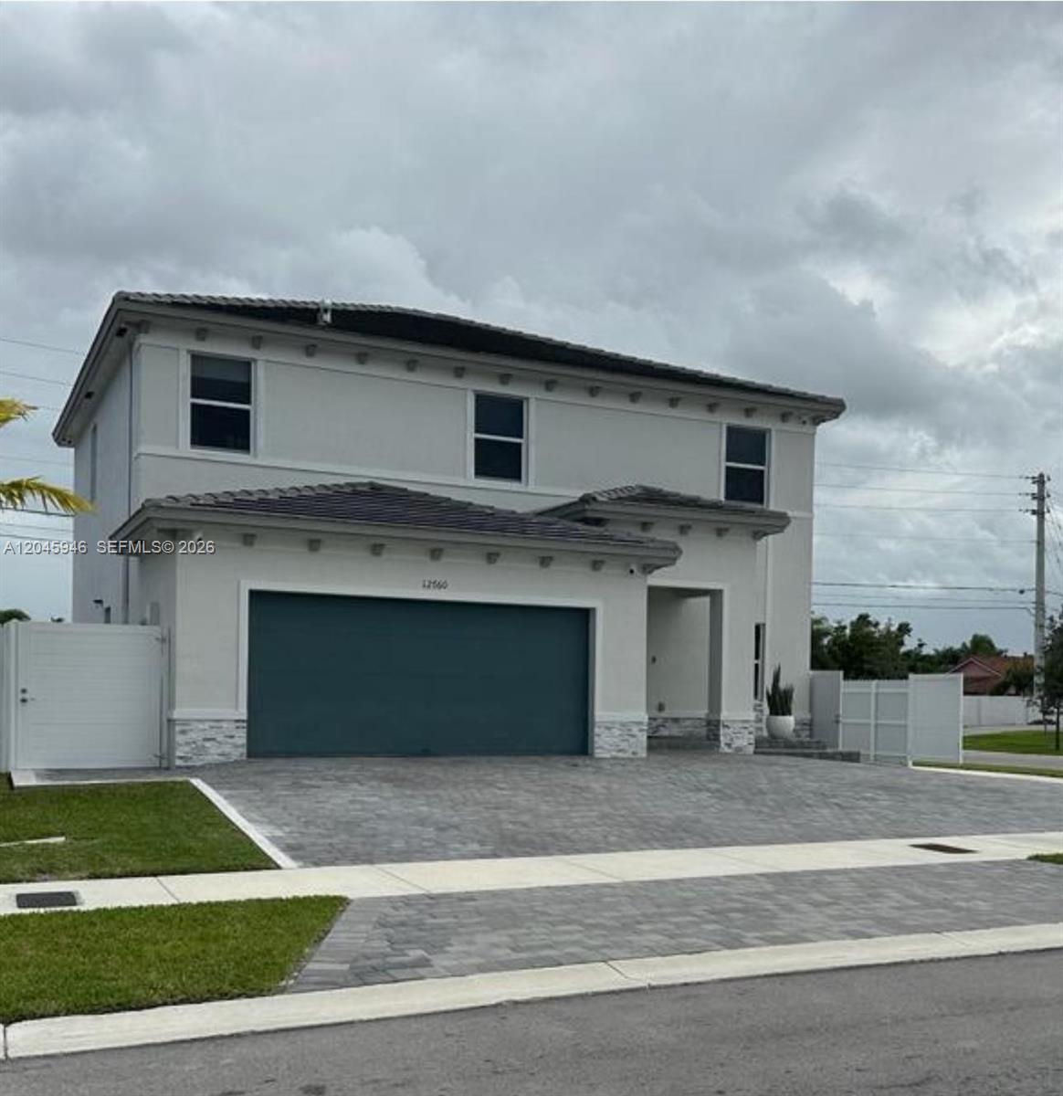 A two-story house with a gray exterior, a dark garage door, and a paved driveway — 12760 SW 215th Ter, Miami FL 33177, MIAMI, FL