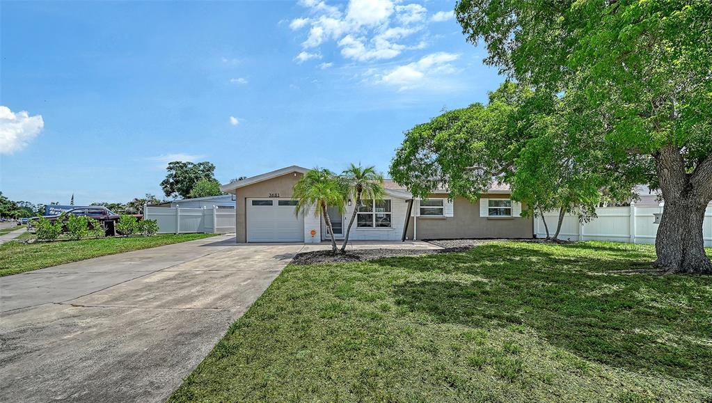 A single-story house with a concrete driveway, a small front lawn, and a large tree — 3681 STOKES DR DRIVE, SARASOTA, FL