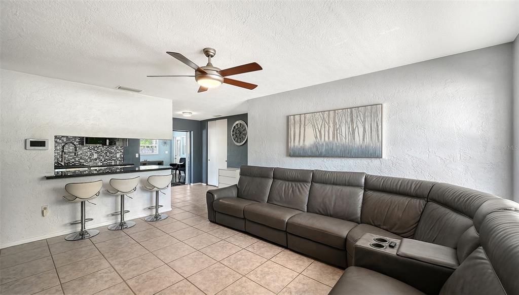 A living room with a gray sectional sofa, a breakfast bar, and tile flooring — 3681 STOKES DR DRIVE, SARASOTA, FL