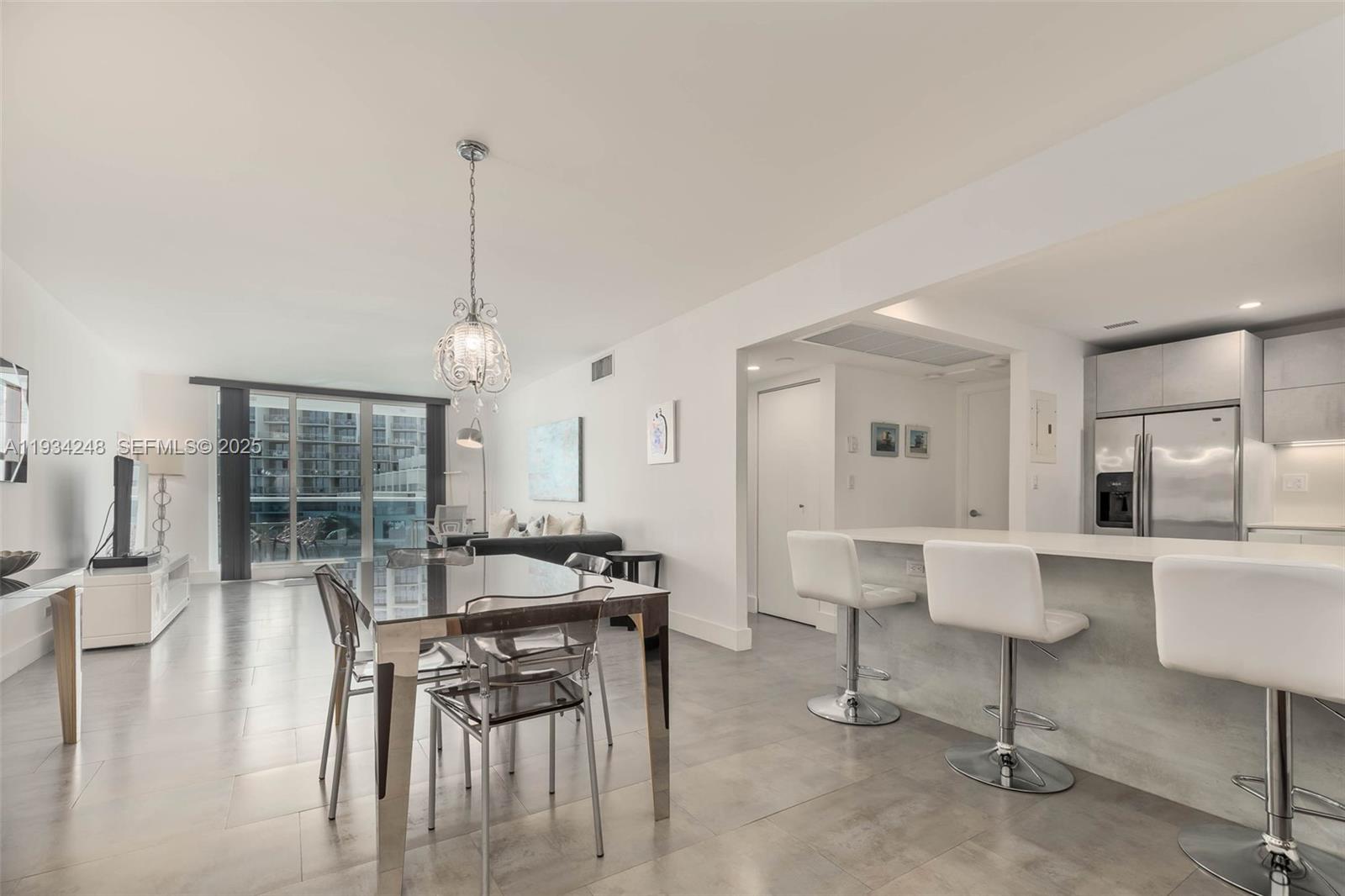 A modern open-concept living area features a dining set, kitchen island with stools, and balcony — 2301 Collins Ave # 507, Miami Beach FL 33139, MIAMI BEACH, FL