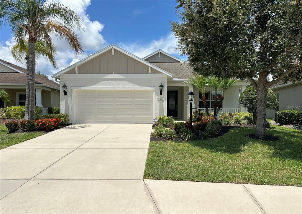 A single-story house with a two-car garage, a palm tree, and a landscaped front yard — 4811 SILVERMOSS DRIVE, SARASOTA, FL