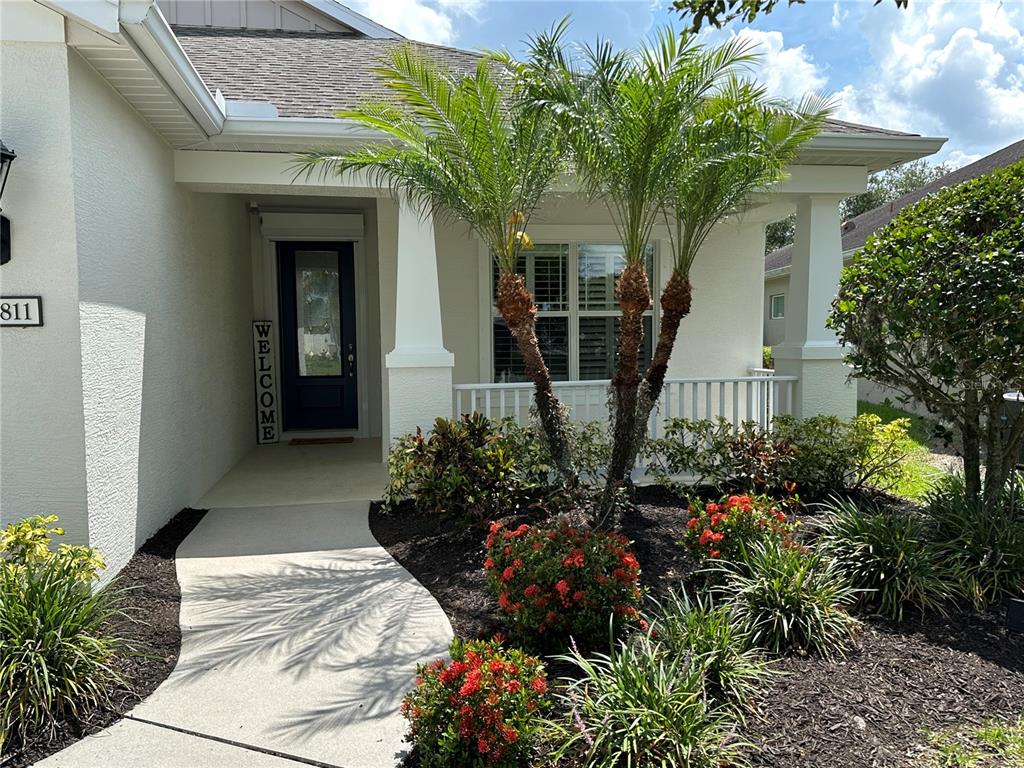 A concrete walkway leads to the front porch of a house with a palm tree — 4811 SILVERMOSS DRIVE, SARASOTA, FL