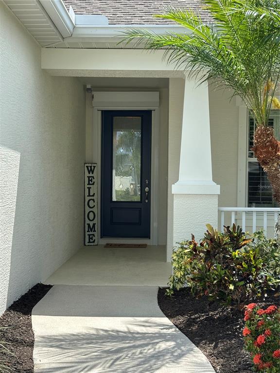 A concrete walkway leads to a covered entryway with a dark blue front door — 4811 SILVERMOSS DRIVE, SARASOTA, FL