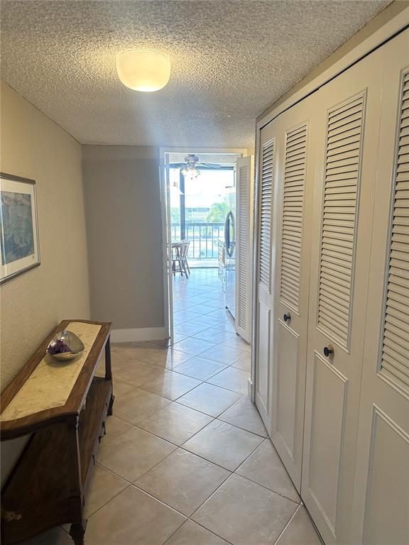 A hallway with tile floors, a wooden console table, and louvered closet doors leads outside — 400 ISLAND WAY UNIT 206, CLEARWATER BEACH, FL