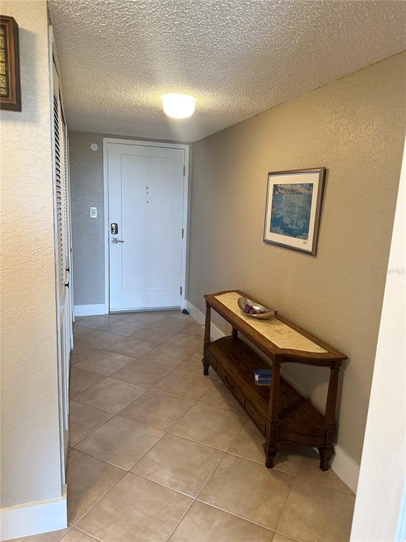 A tiled entryway features a wooden console table, a framed picture, and a white door — 400 ISLAND WAY UNIT 206, CLEARWATER BEACH, FL