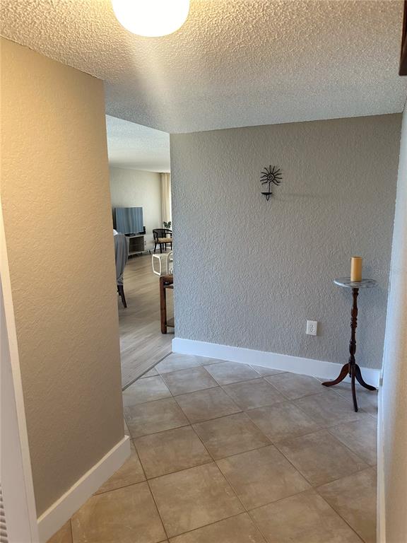 A tiled entryway leads into a living area with light-colored walls and wood-look flooring — 400 ISLAND WAY UNIT 206, CLEARWATER BEACH, FL