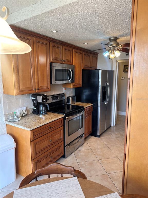 A kitchen features wood cabinets, granite countertops, stainless steel appliances, and tile flooring — 400 ISLAND WAY UNIT 206, CLEARWATER BEACH, FL