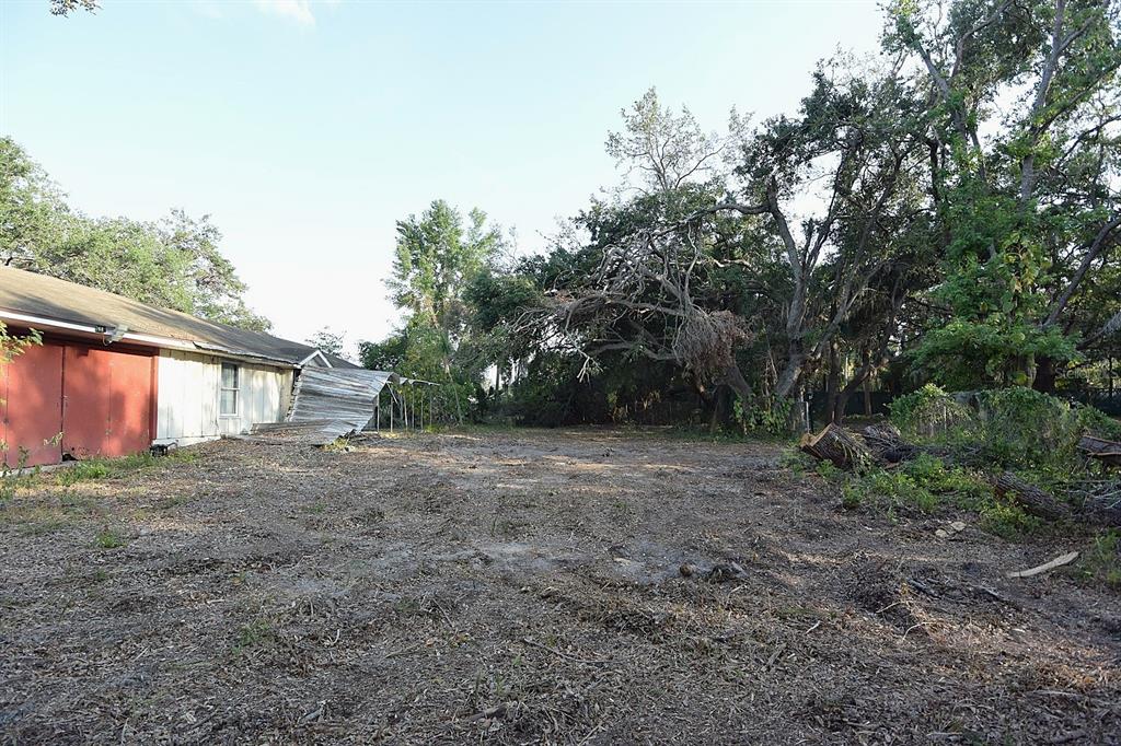 A dirt lot sits next to a white building with red doors and a collapsed awning — 7610 ANNA AVENUE, GIBSONTON, FL