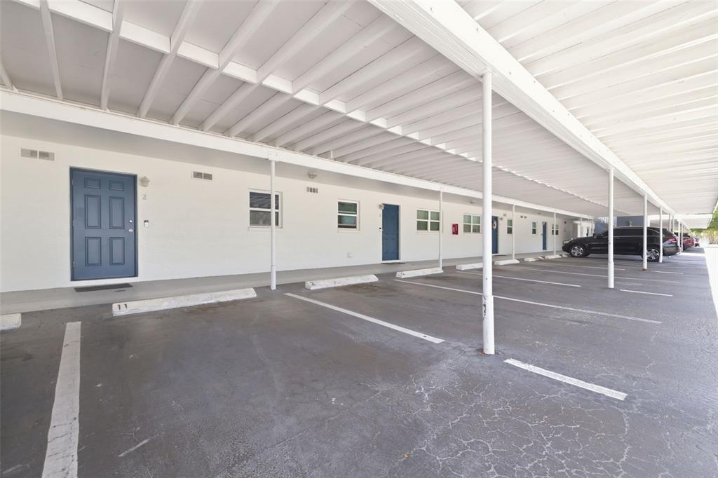 A row of apartment units with blue doors under a covered parking carport — 3717 46TH AVENUE S UNIT 11, ST PETERSBURG, FL
