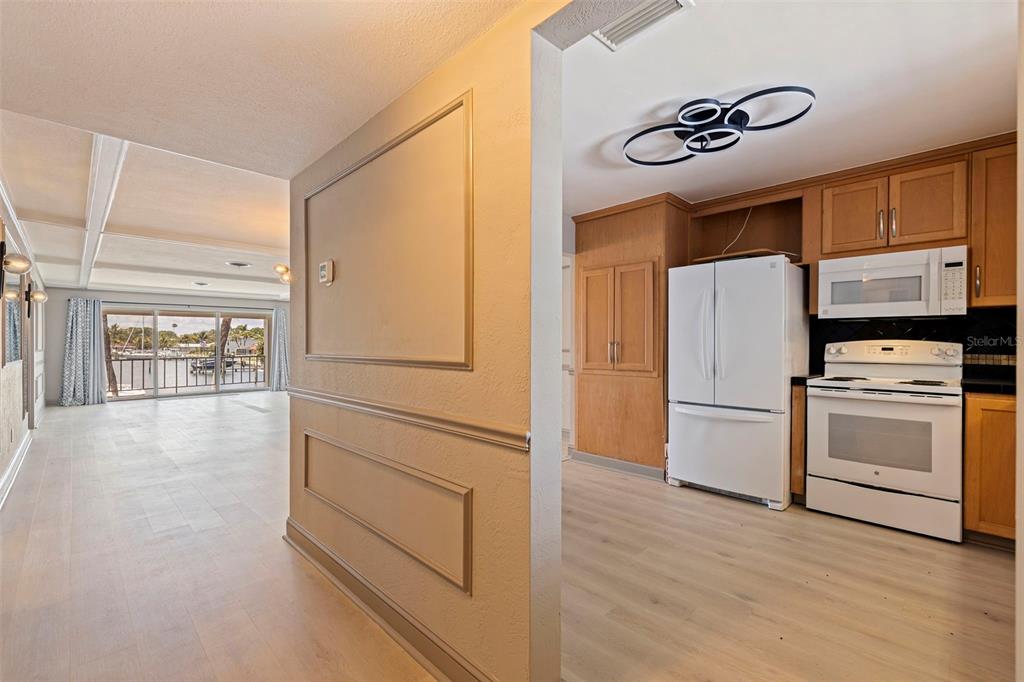 A view from a hallway into a kitchen with wood cabinets and a living area — 3717 46TH AVENUE S UNIT 11, ST PETERSBURG, FL