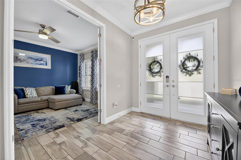 A foyer with wood-look tile flooring leads into a living room with a blue wall — 12444 HORSESHOE BEND DRIVE, LITHIA, FL
