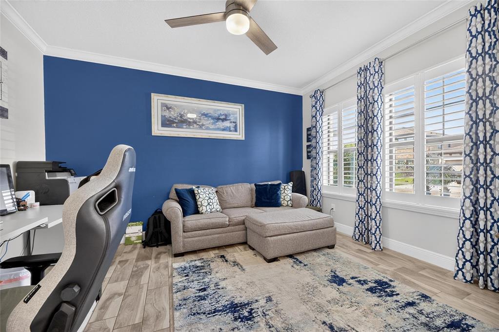 A home office features a blue accent wall, a gray sectional sofa, and wood-look flooring — 12444 HORSESHOE BEND DRIVE, LITHIA, FL
