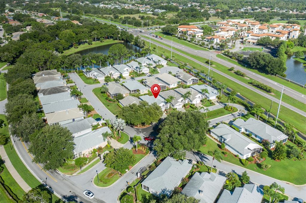 An aerial view shows a residential neighborhood with houses, streets, and a nearby pond — 1239 STADLER DRIVE, NEW PORT RICHEY, FL