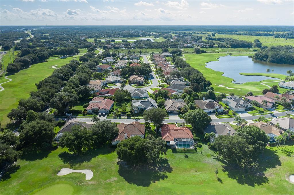An aerial view shows a residential neighborhood surrounded by a golf course and a lake — 1239 STADLER DRIVE, NEW PORT RICHEY, FL
