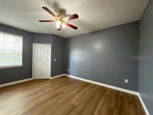 An empty room features gray walls, wood-look flooring, a ceiling fan, and a closet door — 17101 CARRINGTON PARK DRIVE UNIT 415, TAMPA, FL