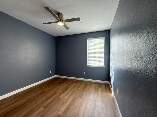 An empty bedroom features dark blue walls, wood-look flooring, and a ceiling fan — 17101 CARRINGTON PARK DRIVE UNIT 415, TAMPA, FL