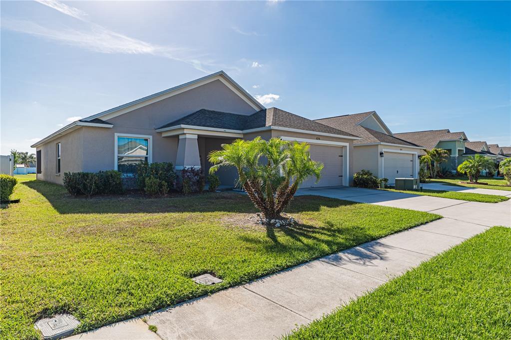 A single-story suburban house with a tan stucco exterior, a two-car garage, and a palm tree — 8256 CAMPBELL CROSSING CIRCLE, LAKELAND, FL
