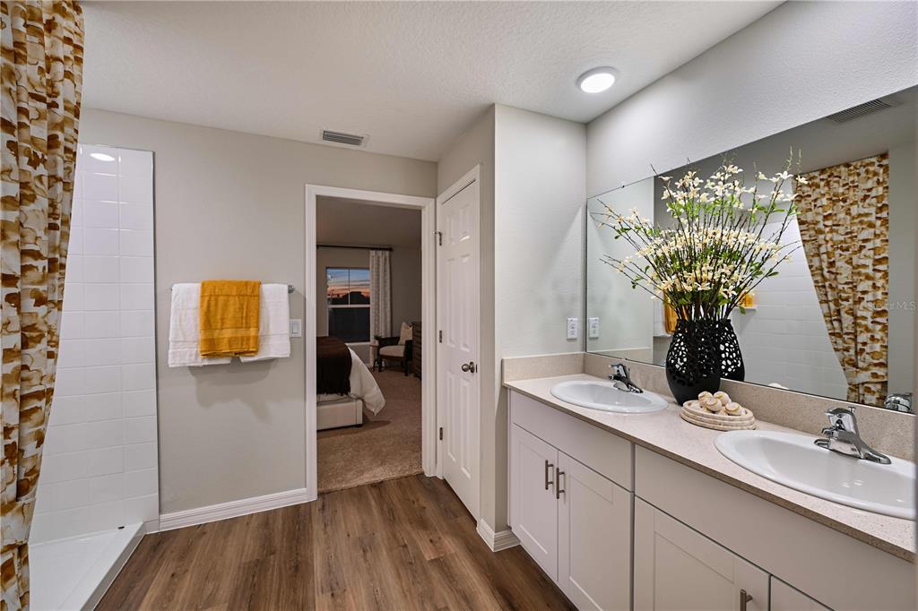 A bathroom features a double vanity, a walk-in shower, and a doorway leading to a bedroom — 1752 VANILLA STREET, HAINES CITY, FL
