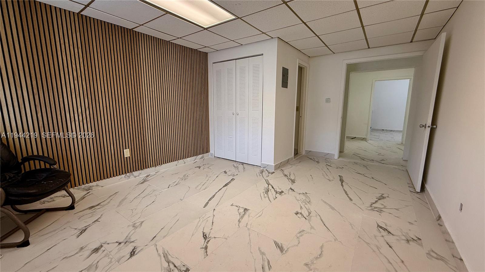 A room features a wood-slat accent wall, white marble-patterned tile flooring, and a closet — 500 NE 25th St # 5, Pompano Beach FL 33064, POMPANO BEACH, FL