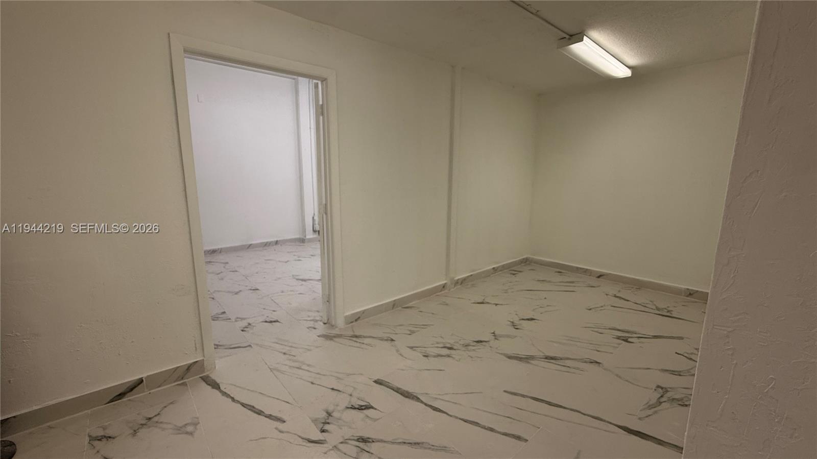 An interior room features white walls, a fluorescent light fixture, and white marble-patterned tile flooring — 500 NE 25th St # 5, Pompano Beach FL 33064, POMPANO BEACH, FL