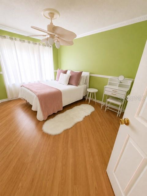 A bedroom features light wood flooring, green walls, a white bed, and a ceiling fan — 3976 ATRIUM DRIVE UNIT U4, ORLANDO, FL