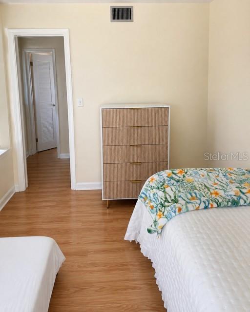 A bedroom features light wood-look flooring, a five-drawer dresser, and a bed with floral bedding — 3976 ATRIUM DRIVE UNIT U4, ORLANDO, FL