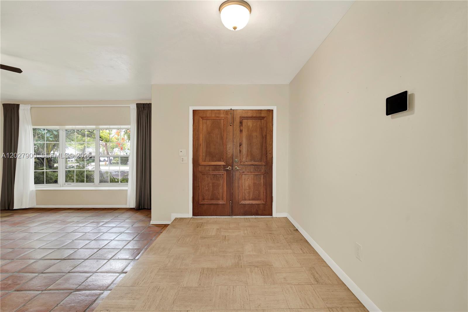 An entryway features double wooden doors, light-colored square floor tiles, and a ceiling light fixture — 6980 SW 104th St, Pinecrest FL 33156, PINECREST, FL