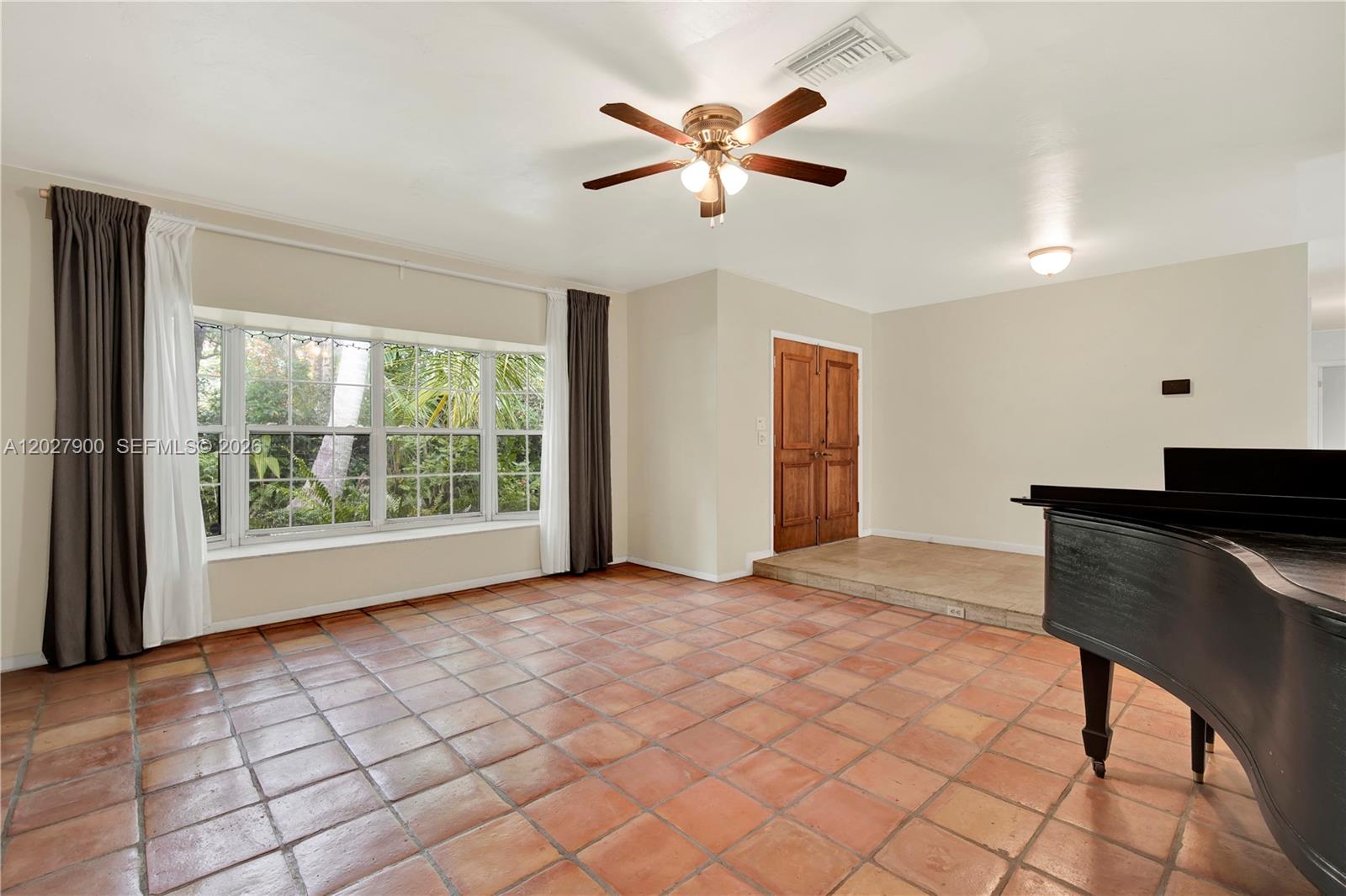 A living room features terracotta tile floors, a ceiling fan, and a large bay window — 6980 SW 104th St, Pinecrest FL 33156, PINECREST, FL