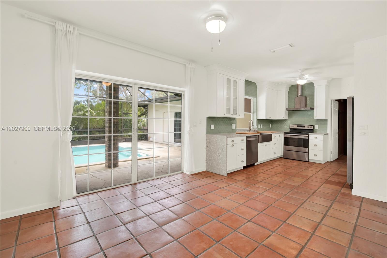 A kitchen with terracotta tile floors opens to a patio with a swimming pool — 6980 SW 104th St, Pinecrest FL 33156, PINECREST, FL