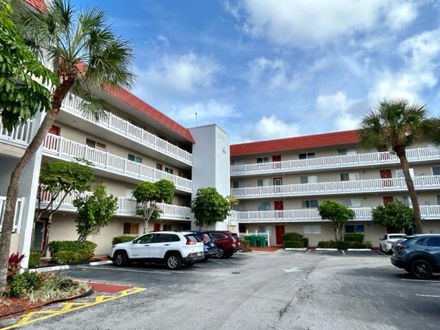A multi-story apartment building with white balconies and a red roof sits above a parking lot — 3601 Inverrary Drive # 306, Lauderhill FL 33319, LAUDERHILL, FL