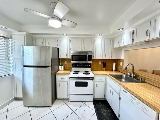 A kitchen features white cabinets, stainless steel appliances, and wood-look countertops — 3601 Inverrary Drive # 306, Lauderhill FL 33319, LAUDERHILL, FL