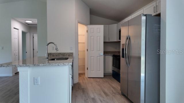 A kitchen with white cabinets, stainless steel appliances, and a granite-topped island — 14973 SW 66 AVE ROAD, OCALA, FL