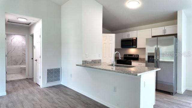 A kitchen with stainless steel appliances, granite countertops, and a breakfast bar overlooks a hallway — 14973 SW 66 AVE ROAD, OCALA, FL