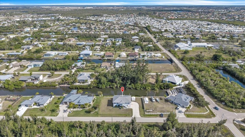 An aerial view shows a waterfront house with a red location pin on a canal — 3900 COLONY COURT, PUNTA GORDA, FL