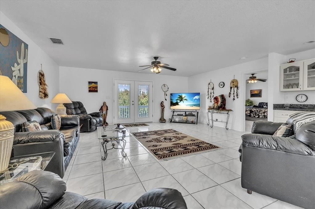 A living room features white tile floors, black leather furniture, and a ceiling fan — 3900 COLONY COURT, PUNTA GORDA, FL