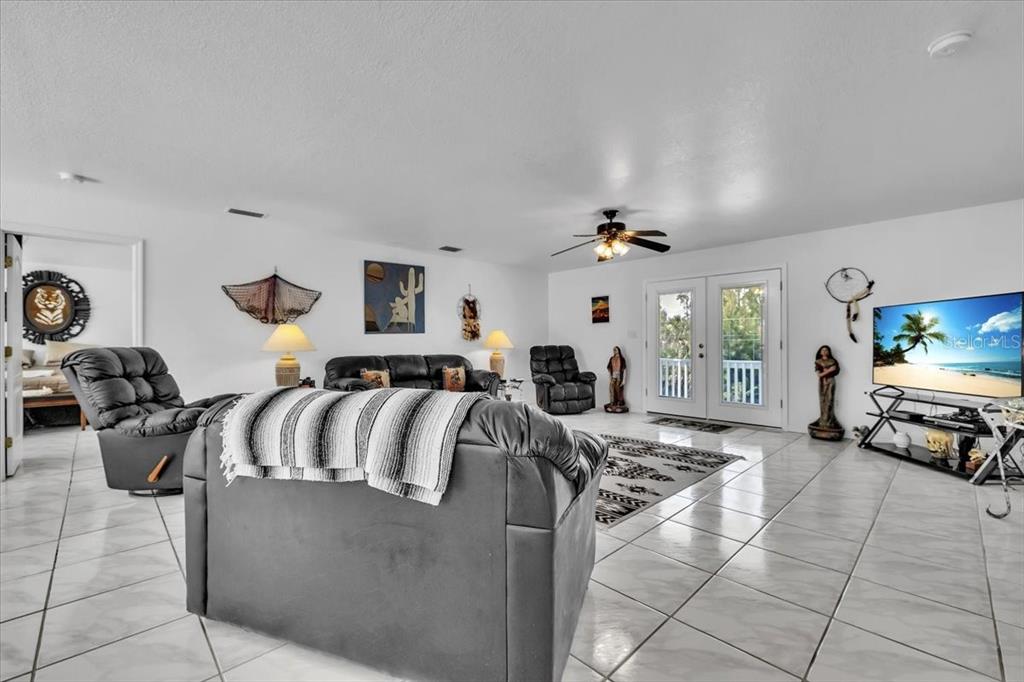 A living room features white tile floors, a black leather sofa, and a television — 3900 COLONY COURT, PUNTA GORDA, FL
