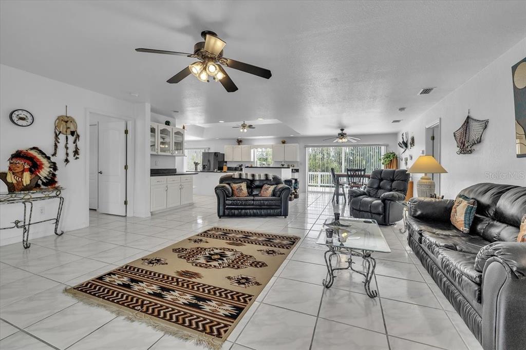 A spacious living room with white tile floors, leather furniture, and a patterned area rug — 3900 COLONY COURT, PUNTA GORDA, FL