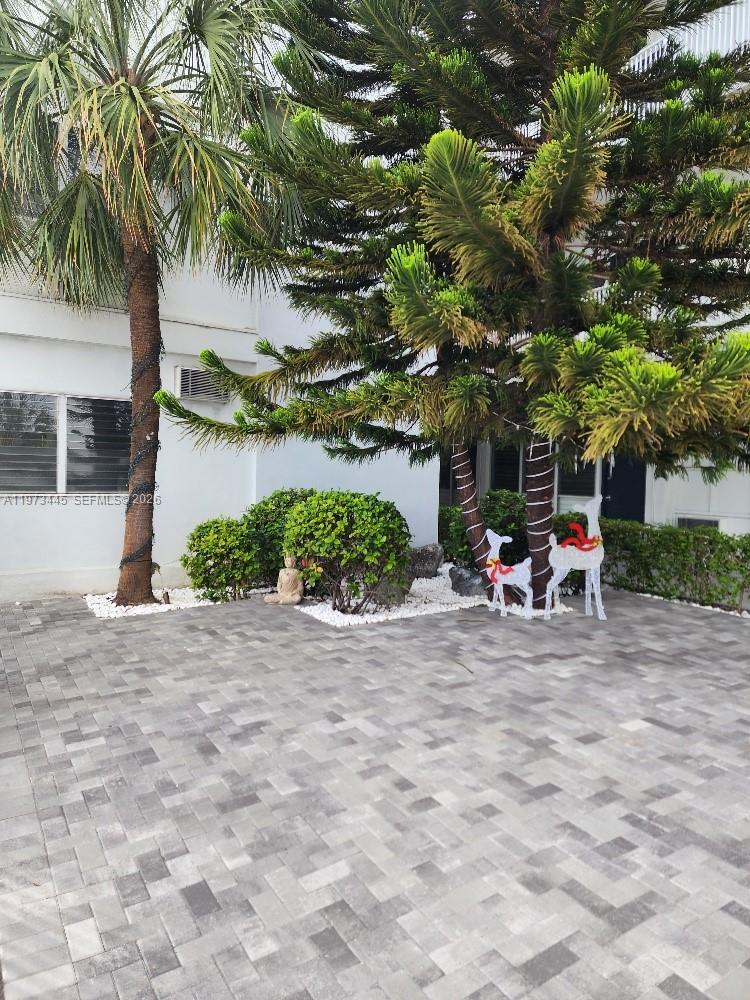 A paved courtyard features a palm tree, a large evergreen, and decorative holiday reindeer figures — 2101 Normandy Dr # 310, Miami Beach FL 33141, MIAMI BEACH, FL